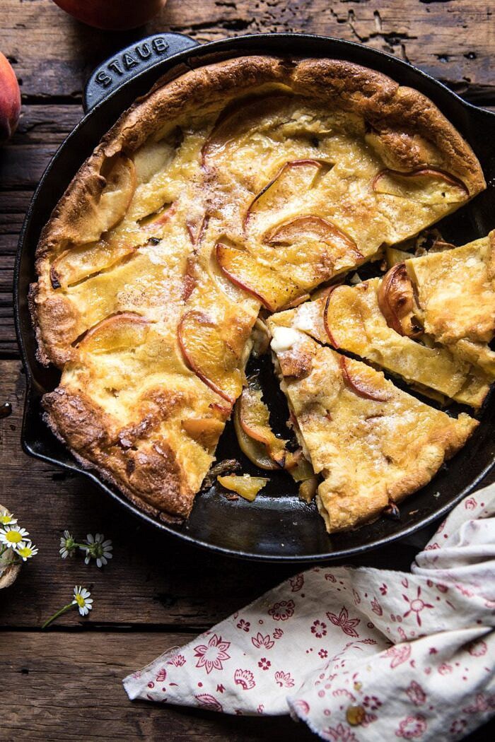 overhead photo of cut into Browned Butter Cinnamon Peach Dutch Baby with butter