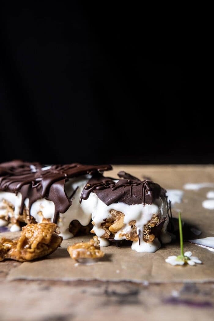 Chocolate Caramel Crunch Ice Cream Bars | halfbakedharvest.com #cereal #chocolate #icecream #dessert #summer side angle photo of Chocolate Caramel Crunch Ice Cream Bars broken in half and melting