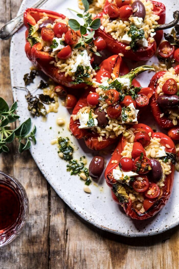 Greek Orzo Stuffed Red Peppers with Lemony Basil Tomatoes | halfbakedharvest.com #healthy #summerrecipes #easy #dinner #greek side angle close up photo of Greek Orzo Stuffed Red Peppers with Lemony Basil Tomatoes