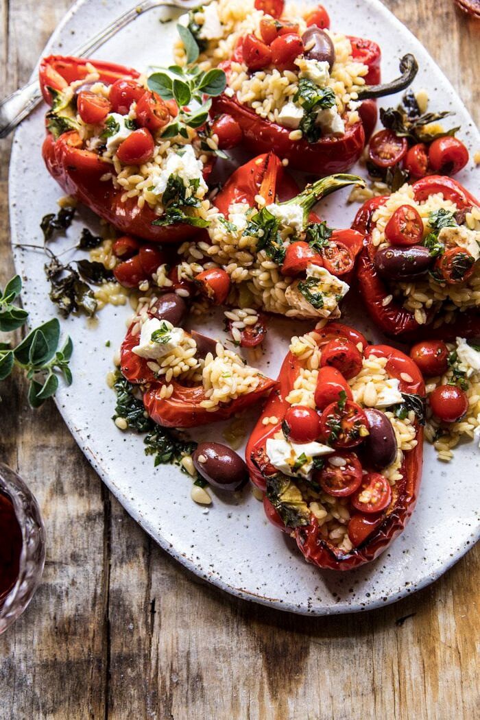 Greek Orzo Stuffed Red Peppers with Lemony Basil Tomatoes | halfbakedharvest.com #healthy #summerrecipes #easy #dinner #greek overhead photo of Greek Orzo Stuffed Red Peppers with Lemony Basil Tomatoes cut in half to expose the filling