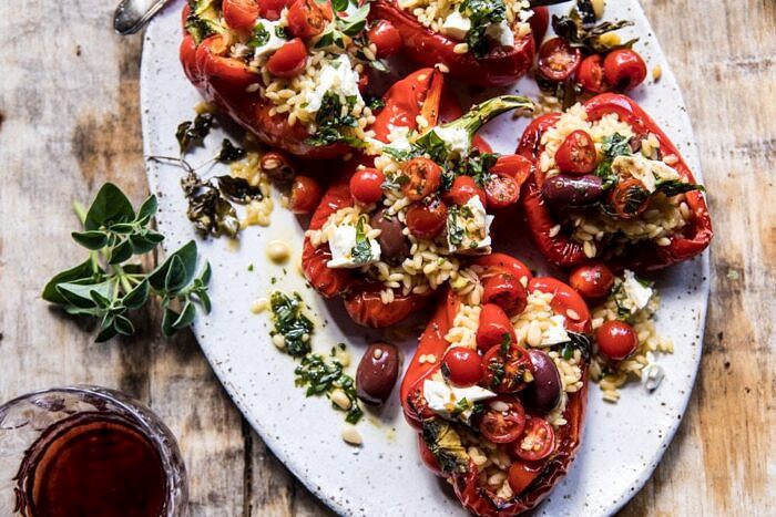 Greek Orzo Stuffed Red Peppers with Lemony Basil Tomatoes | halfbakedharvest.com #healthy #summerrecipes #easy #dinner #greek overhead horizontal photo of Greek Orzo Stuffed Red Peppers with Lemony Basil Tomatoes