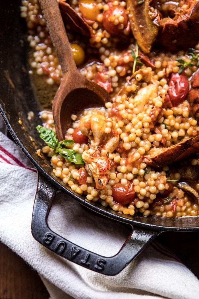 overhead close up photo of One Pot Tomato Basil Lobster and Herbed Pearl Couscous with wooden spoon