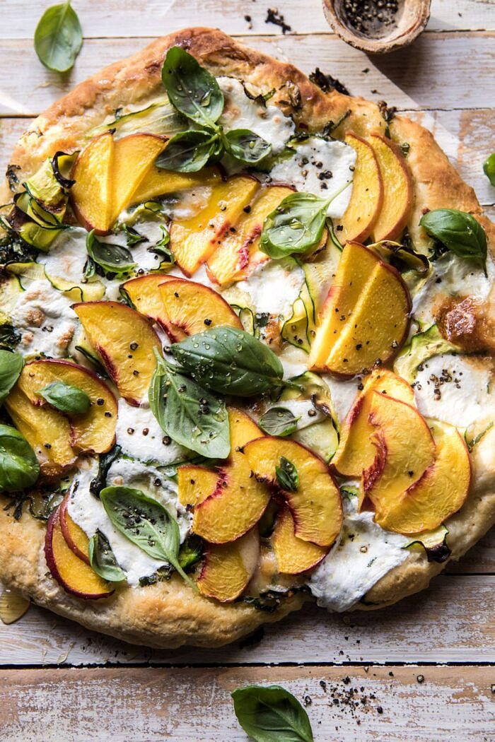 Pesto Zucchini and Peach Pizza with Burrata | halfbakedharvest.com #peach #pizza #summer #easyrecipes overhead photo of Pesto Zucchini and Peach Pizza with Burrata with sunlight on pizza