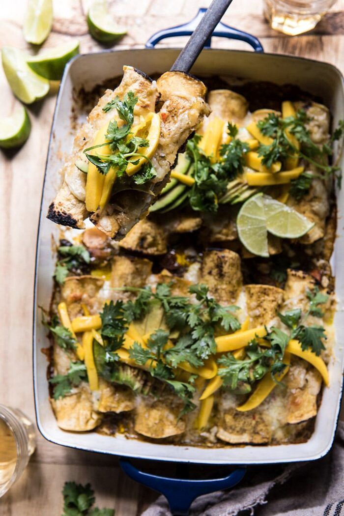 Salsa Verde Chicken and Zucchini Enchiladas with Mango | halfbakedharvest.com #mexican #enchiladas #zucchini #summerrecipes #easy action shot Salsa Verde Chicken and Zucchini Enchiladas with Mango being removed from the baking dish with a serving spoon