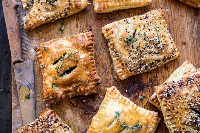 Caramelized Onion, Spinach, and Cheddar Flaky Pastries | halfbakedharvest.com #onions #tarts #fall #autumnrecipes #easy #holiday #appetizer overhead horizontal photo of Caramelized Onion, Spinach, and Cheddar Flaky Pastries