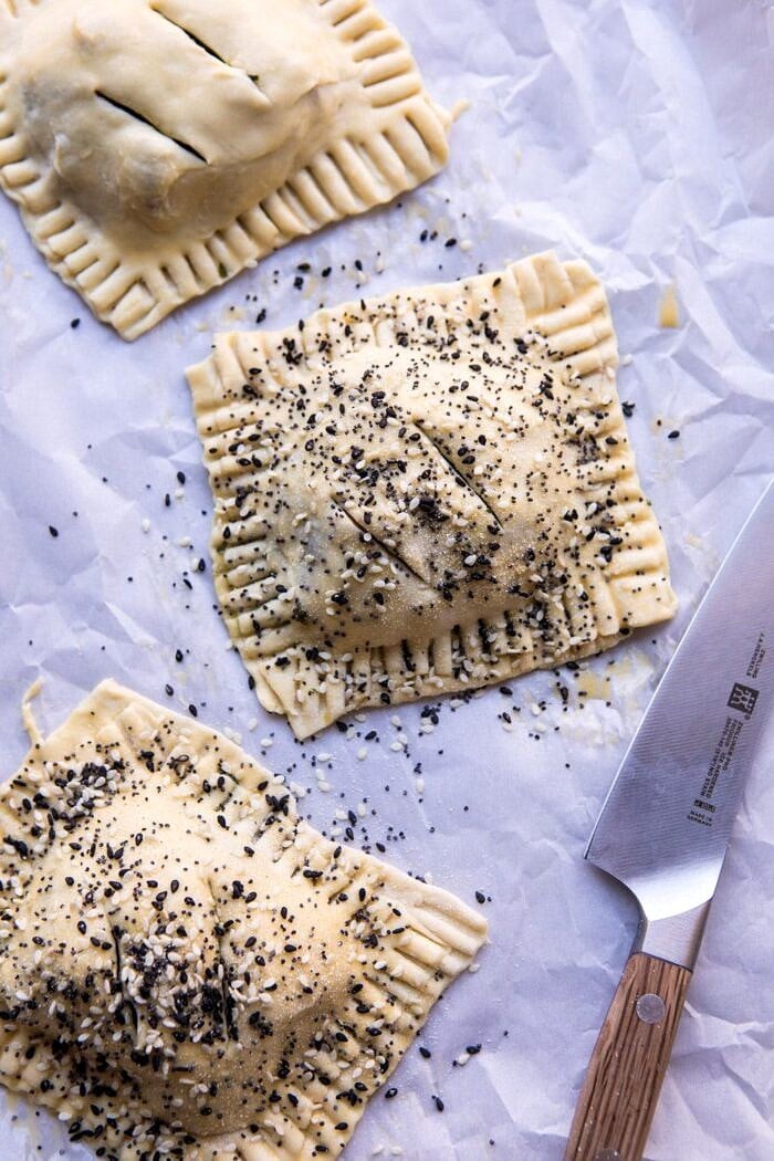 Caramelized Onion, Spinach, and Cheddar Flaky Pastries | halfbakedharvest.com #onions #tarts #fall #autumnrecipes #easy #holiday #appetizer overhead photo Caramelized Onion, Spinach, and Cheddar Flaky Pastries before baking on baking sheet