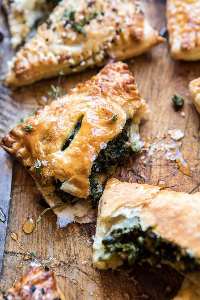 Caramelized Onion, Spinach, and Cheddar Flaky Pastries | halfbakedharvest.com #onions #tarts #fall #autumnrecipes #easy #holiday #appetizer side angle photo of broken Caramelized Onion, Spinach, and Cheddar Flaky Pastry