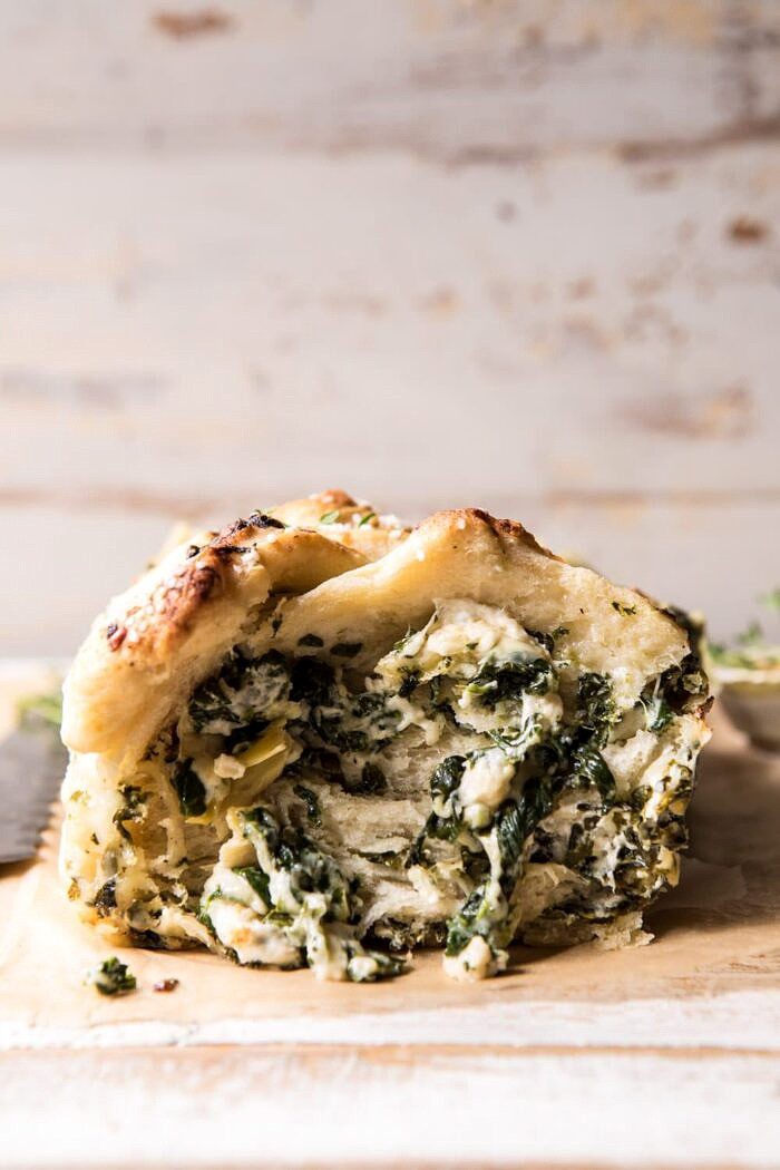Herbed Spinach and Artichoke Pull Apart Pretzel Bread | halfbakedharvest.com #bread #appetizer #gamedayrecipes #easyrecipes front on photo Herbed Spinach and Artichoke Pull Apart Pretzel Bread with piece missing to expose the filling