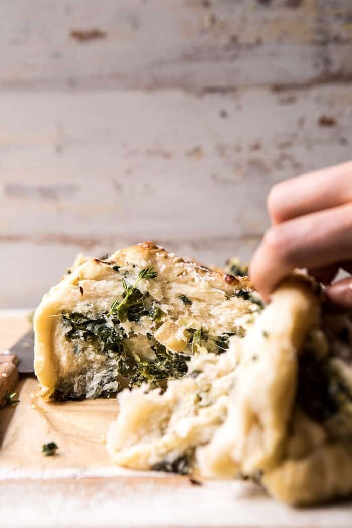 Herbed Spinach and Artichoke Pull Apart Pretzel Bread | halfbakedharvest.com #bread #appetizer #gamedayrecipes #easyrecipes front on, close up photo of Herbed Spinach and Artichoke Pull Apart Pretzel Bread being pilled open