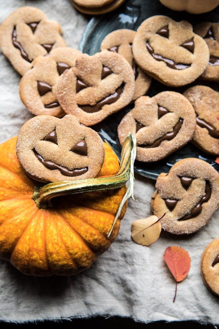 Milk Chocolate Stuffed Jack-O'-Lantern Cookies | halfbakedharvest.com #halloween #thanksgiving #cookies #easyrecipes #chocolate #holidayrecipes #fallrecipes Milk Chocolate Stuffed Jack-O'-Lantern Cookies sitting on top of mini pumpkin
