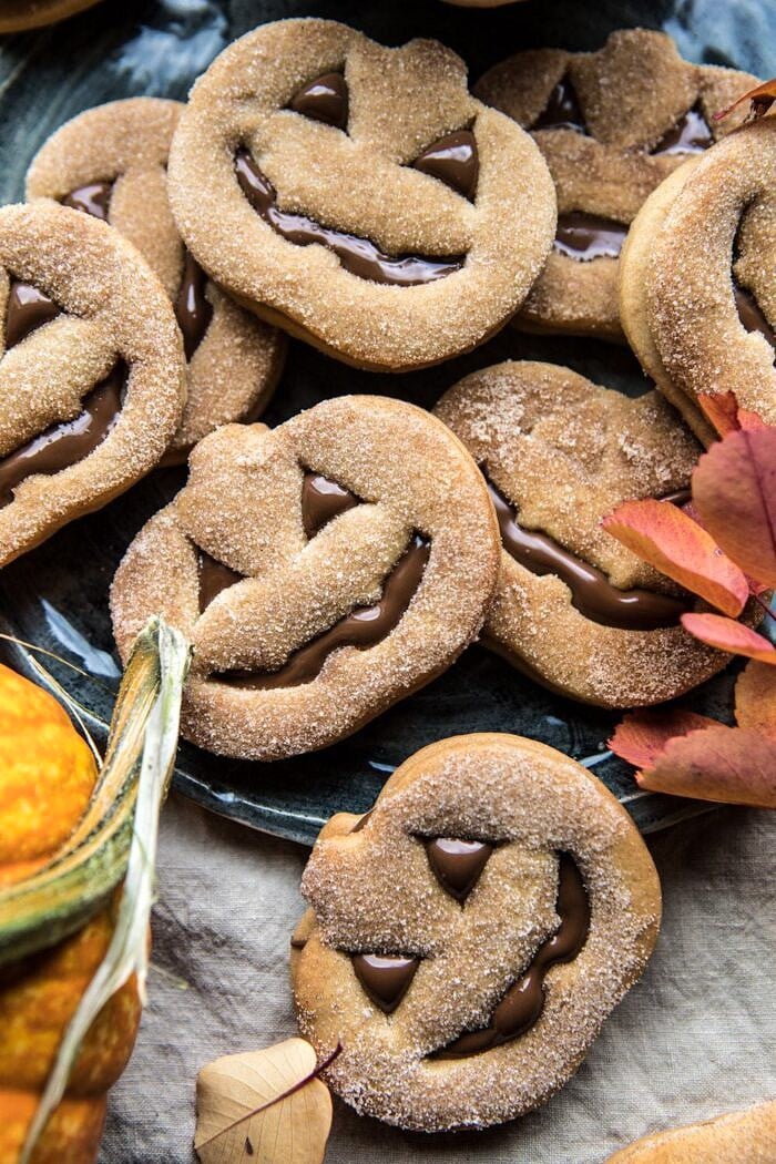 Milk Chocolate Stuffed Jack-O'-Lantern Cookies | halfbakedharvest.com #halloween #thanksgiving #cookies #easyrecipes #chocolate #holidayrecipes #fallrecipes close up overhead photo of Milk Chocolate Stuffed Jack-O'-Lantern Cookies on plate