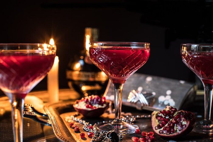 The Half Blood Prince Cocktail | halfbakedharvest.com #cocktails #halloween #pomegranate #fall #autumn horizontal photo of The Half Blood Prince Cocktail with candles in photo