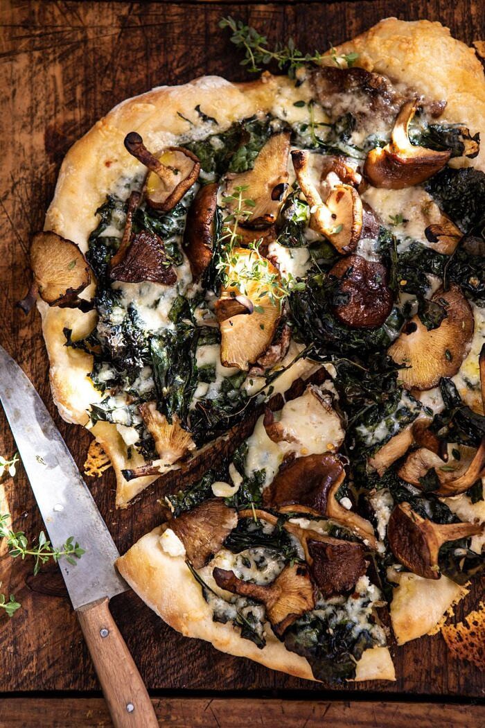 overhead close up photo of Roasted Mushroom Kale Pizza with slice cut and knife in photo