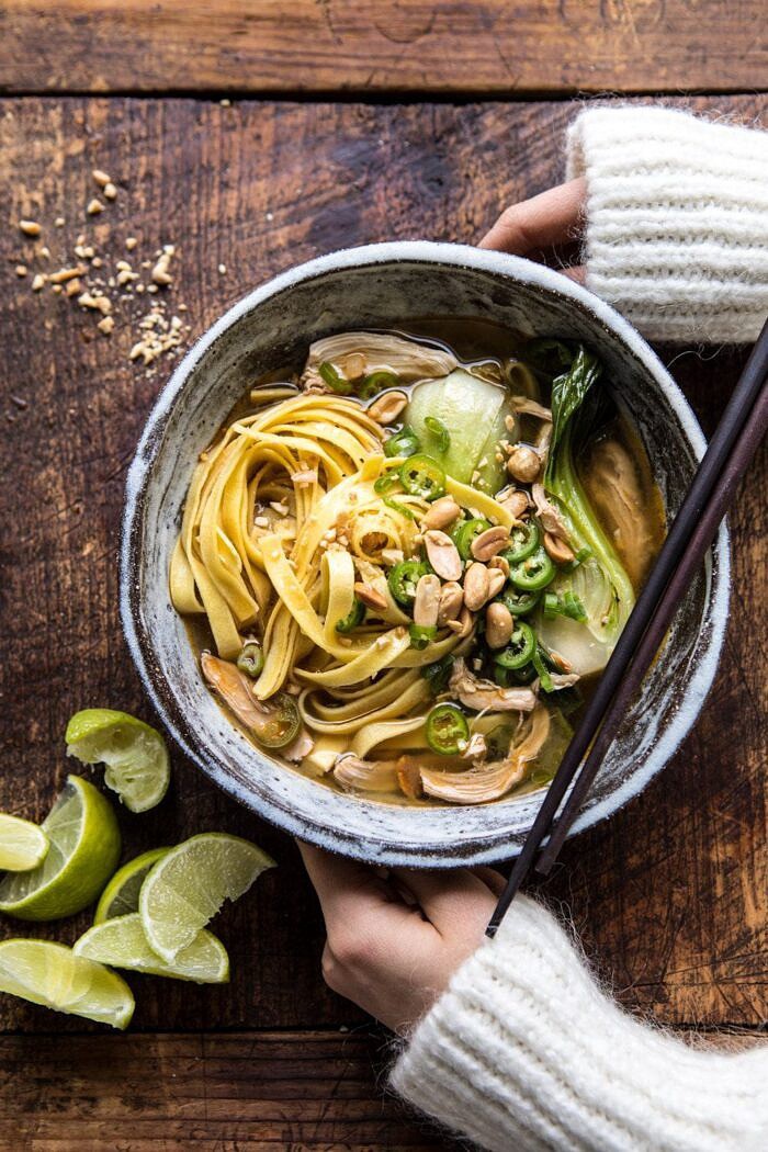 Ginger Peanut Chicken Noodle Soup | halfbakedharvest.com #soup #healthyrecipe #chickensoup #easyrecipes overhead photo of Ginger Peanut Chicken Noodle Soup with hands on bowl