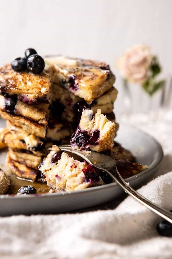Blueberry Lemon Ricotta Pancakes | halfbakedharvest.com #blueberrypancakes #pancakes #brunch #breakfast #lemon Blueberry Lemon Ricotta Pancakes with fork in pancakes and bite taken out