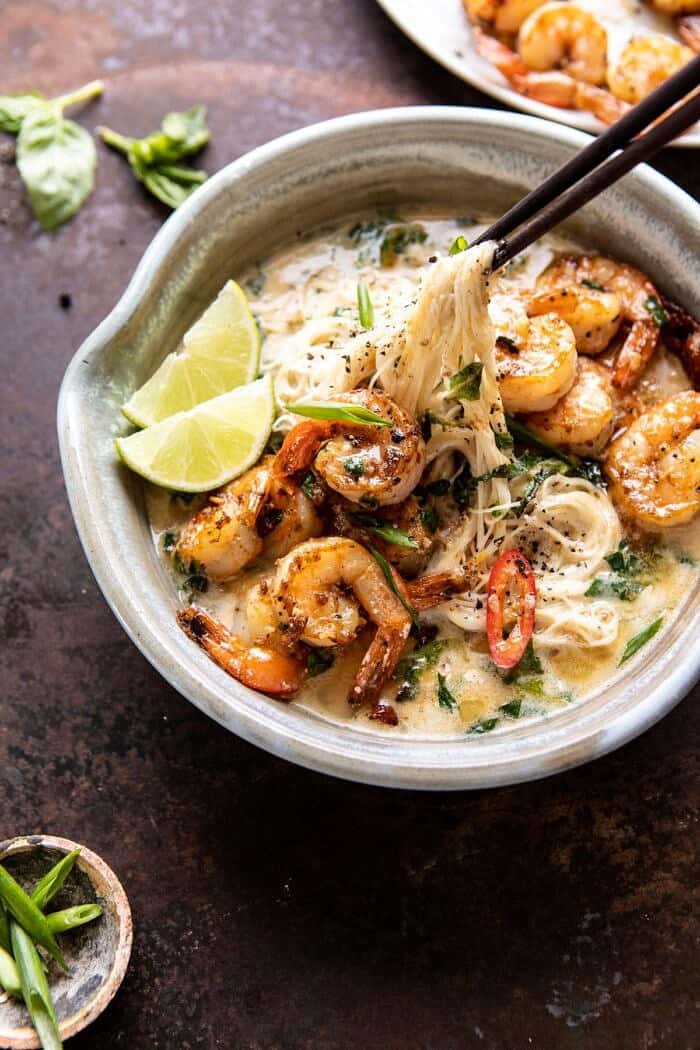 Saucy Garlic Butter Shrimp with Coconut Milk and Rice Noodles | halfbakedharvest.com #shrimp #easyrecipes #healthy #seafood #thairecipes #asian side angled photo of Saucy Garlic Butter Shrimp with Coconut Milk and Rice Noodles being pulled up out of the bowl with chopsticks