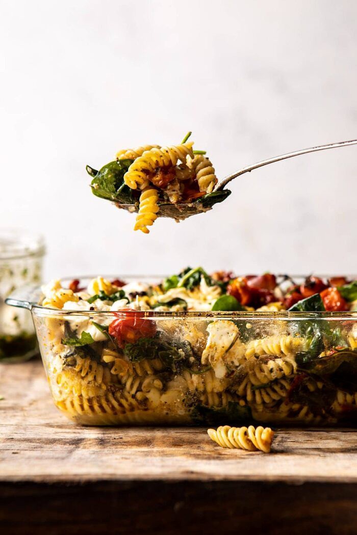 Caprese Pesto Pasta Bake | halfbakedharvest.com #caprese #pesto #pasta #easyrecipes side angled photo of Caprese Pesto Pasta Bake with spoon coming out of dish