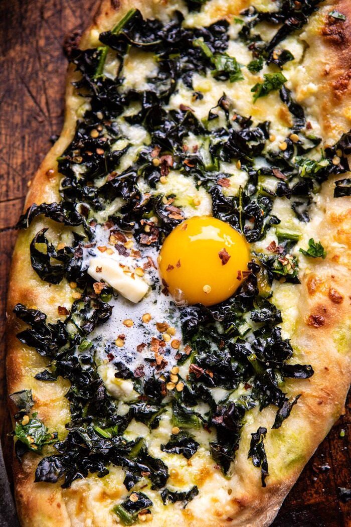 Khachapuri (Georgian Cheese Bread) with Kale and Herb Sauce | halfbakedharvest.com #pizza #easyrecipes #cheese #bread overhead close up photo of Khachapuri (Georgian Cheese Bread) with Kale and Herb Sauce