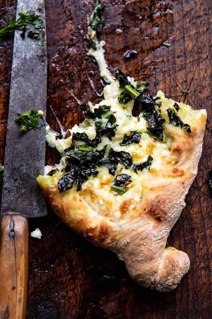 Khachapuri (Georgian Cheese Bread) with Kale and Herb Sauce | halfbakedharvest.com #pizza #easyrecipes #cheese #bread single piece of Khachapuri (Georgian Cheese Bread) with Kale and Herb Sauce