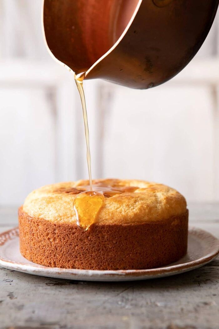 lemon honey syrup being drizzled on Lemon Coconut Naked Cake 