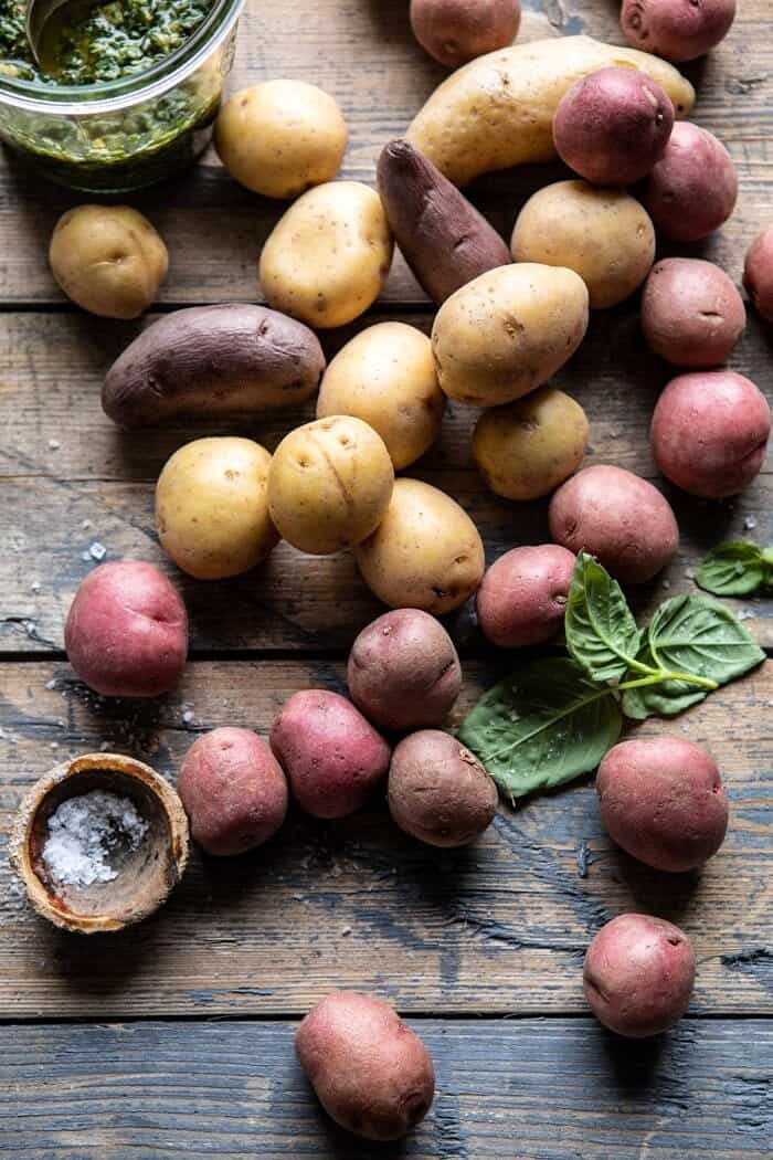 Pesto Potato Salad | halfbakedharvest.com #potatosalad #easyrecipes #pesto #summerrecipes over head photo if raw potatoes with pesto jar in the corner