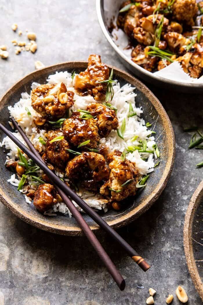 Better Than Takeout Kung Pao Cauliflower | halfbakedharvest.com #vegan #healthyrecipes #easyrecipes #vegetables side angled close up photo of Better Than Takeout Kung Pao Cauliflower in a bowl with rice an chopsticks