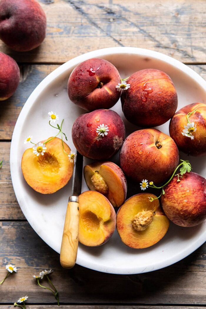 Peaches in serving bowl with chamomile flowers