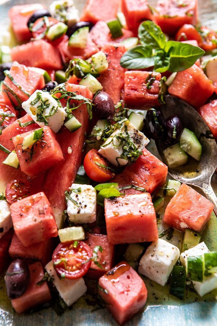 close up side angled photo of Greek Watermelon Feta Salad with Basil Vinaigrette with spoon in salad