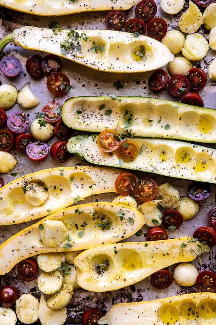 Spicy Chickpea and Cheese Stuffed Zucchini | halfbakedharvest.com #healthy #easyrecipes #summerrecipes #zucchini Zucchini and tomatoes on baking sheet before roasting