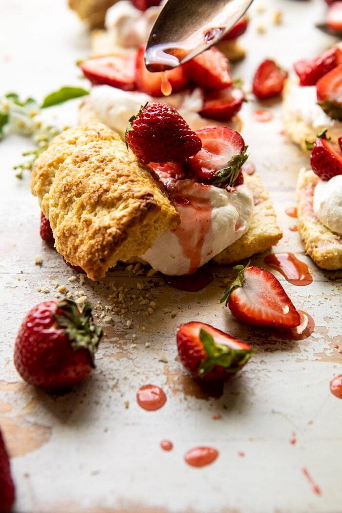 The Best Strawberry Shortcakes | halfbakedharvest.com #shortcakes #strawberries #summer #strawberry side angled photo of The Best Strawberry Shortcakes with strawberry juice being drizzled on berries