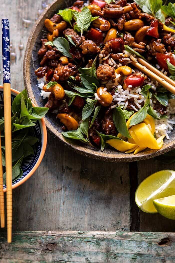 Better Than Takeout Sweet Thai Basil Chicken | halfbakedharvest.com #easyrecipes #20minutes #thaichicken #ricebowl #healthy side angled close up photo of Better Than Takeout Sweet Thai Basil Chicken with chopsticks in photo