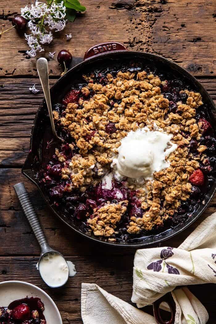 Buttery Cherry Berry Skillet Crisp | halfbakedharvest.com #berries #summerrecipes #easyrecipes #cherries overhead photo of Buttery Cherry Berry Skillet Crisp in skillet with 1 scoop of ice cream and spoon in skillet