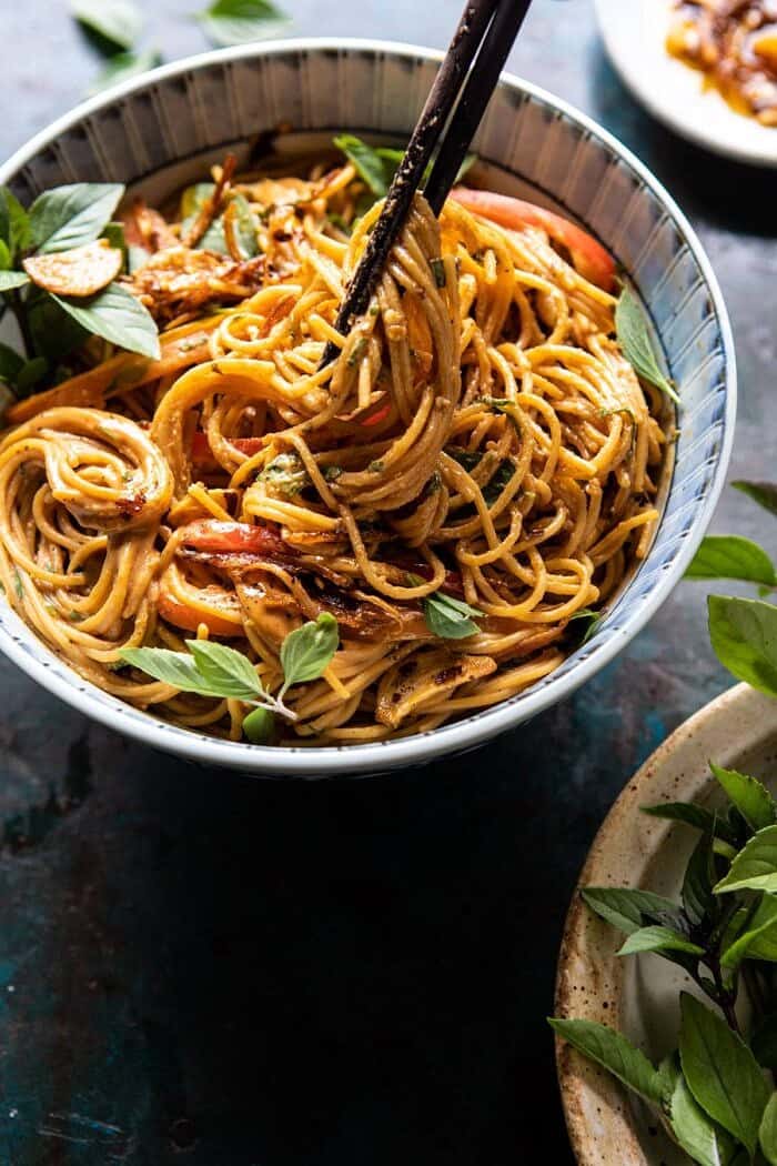 Spicy Peanut Noodles with Chili Garlic Oil | halfbakedharvest.com #peanutnoodles #easyrecipes #dinner #healthy side angled photo of Spicy Peanut Noodles with Chili Garlic Oil and chopsticks pulling up noodles out of the bowl