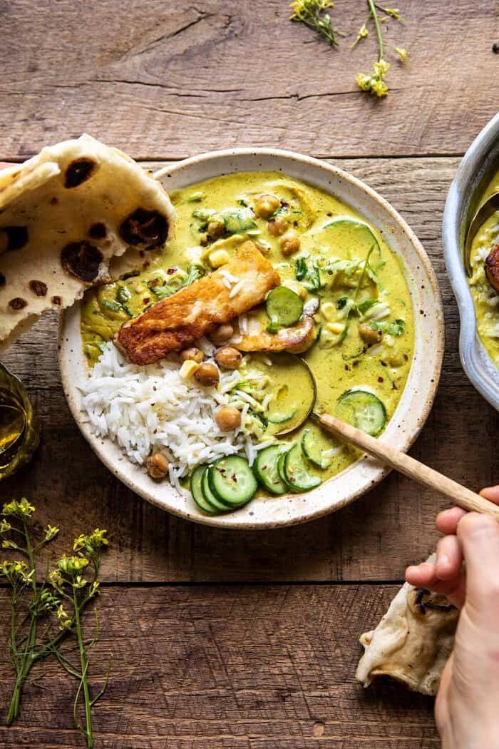 Summer Coconut Chickpea Curry with Rice and Fried Halloumi | halfbakedharvest.com #coconut #vegan #curry #easyrecipes #summer overhead photo of Summer Coconut Chickpea Curry with Rice and Fried Halloumi with hands on bowl and spoon in bowl