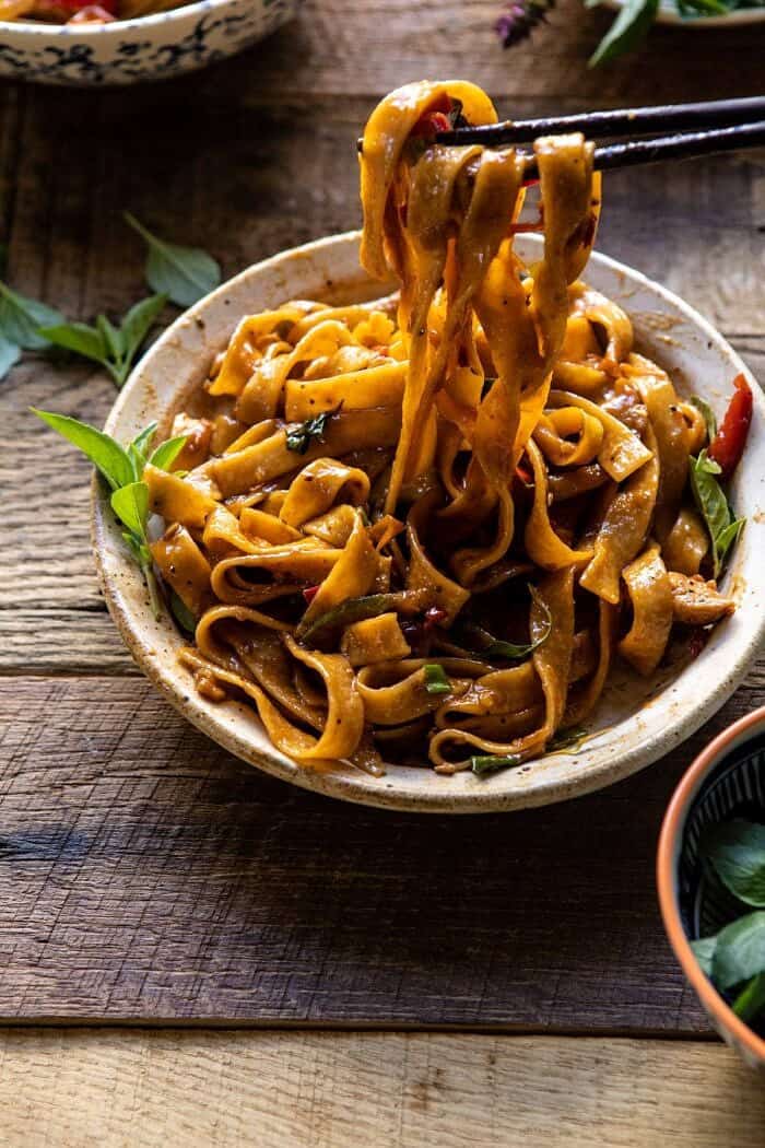 Better Than Takeout Thai Drunken Noodles | halfbakedharvest.com #takeout #noodles #weeknightrecipe #Thai side angled photo of Better Than Takeout Thai Drunken Noodles with chopsticks pulling noodles out of the bowl to eat