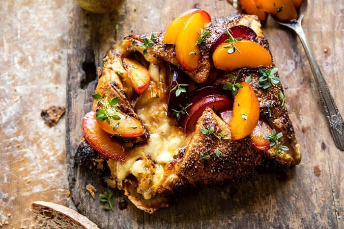 horizontal photo of Pastry Wrapped Baked Brie with Thyme Butter Roasted Plums | halfbakedharvest.com #brie #easyrecipes #appetizer #summer #fall