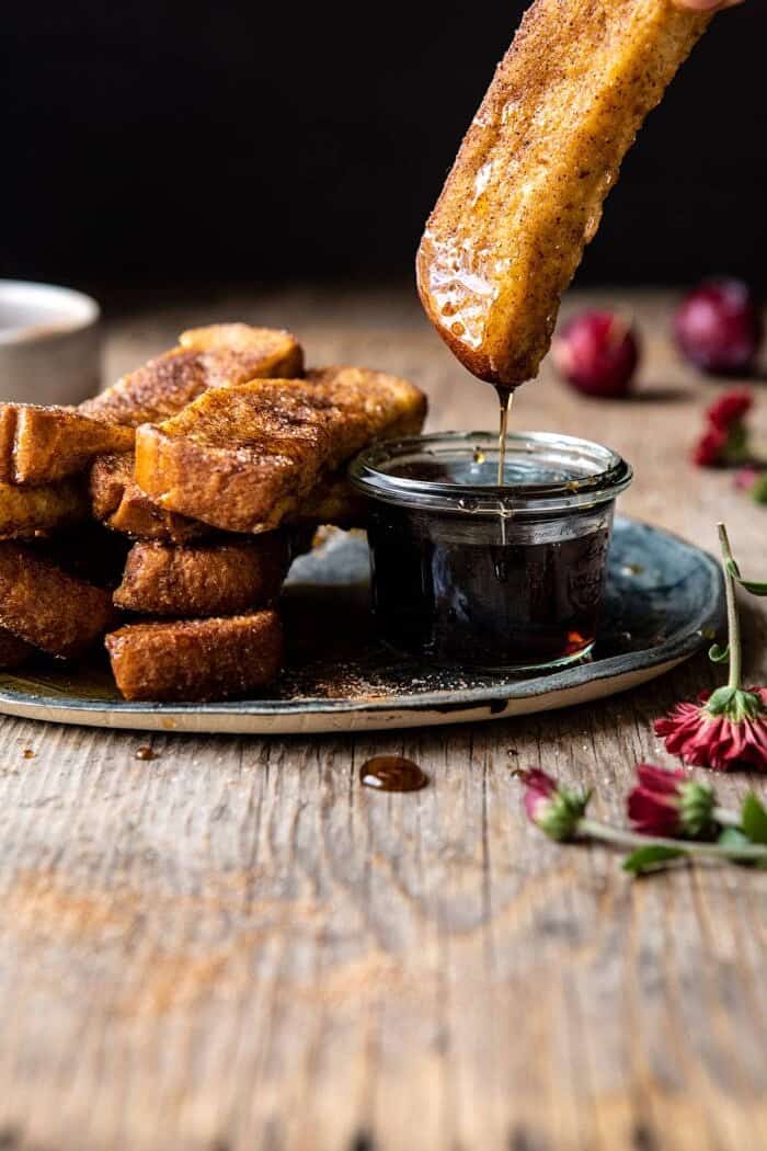 side angled photo of Cinnamon Sugar French Toast Sticks being dipped into maple syurp