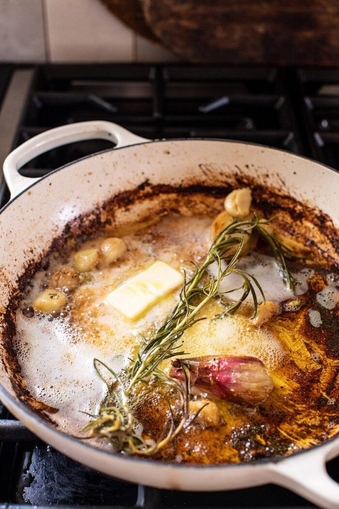Prosciutto Apple and Sage Butter Chicken with Cider Pan Sauce | halfbakedharvest.com #chicken #apples #fallrecipes #skillet side angled photo of butter, garlic, shallots, and rosemary in skillet on stove