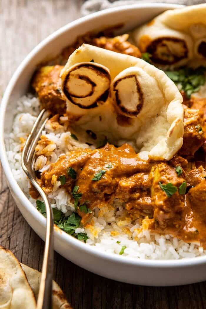Super Simple Coconut Chicken Tikka Masala | halfbakedharvest.com #Indian #healthyrecipes #chicken #easy #fast side angled close up photo of Super Simple Coconut Chicken Tikka Masala with fork in bowl