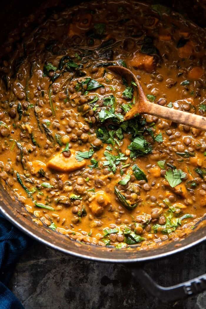 Sweet Potato Lentil Curry with Crispy Sesame Chickpeas | halfbkaedharvest.com #healthy #vegan #easyrecipes #fallrecipes overhead photo of Sweet Potato Lentil Curry in pot with wooden spoon in curry