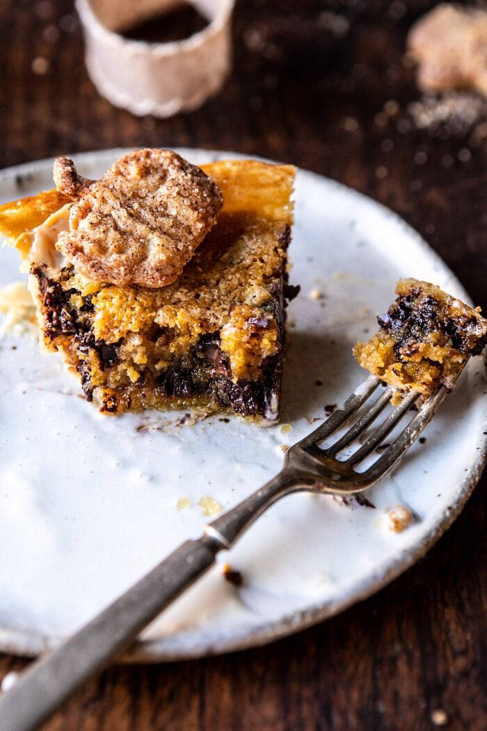 Gooey Chocolate Chip Cookie Pumpkin Pie | halfbakedharvest.com #cookiepie #thanksgiving #pumpkinpie side angled photo of Gooey Chocolate Chip Cookie Pumpkin Pie slice with bites taken out of pie