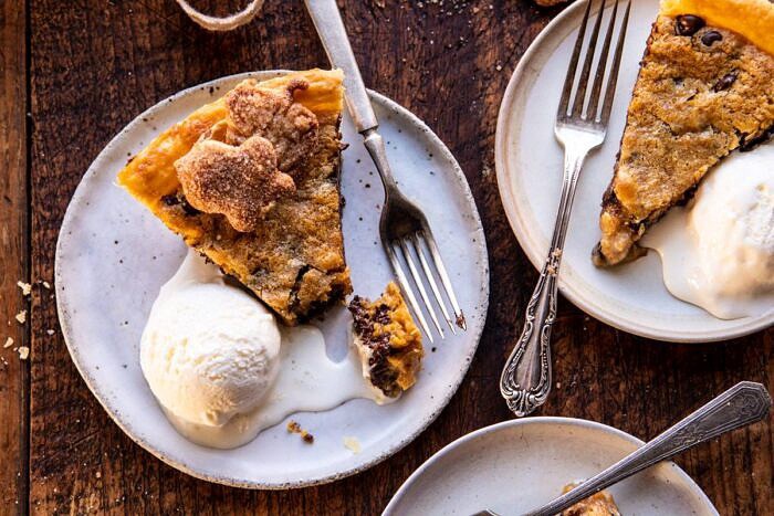 Gooey Chocolate Chip Cookie Pumpkin Pie | halfbakedharvest.com #cookiepie #thanksgiving #pumpkinpie horizontal photo of Gooey Chocolate Chip Cookie Pumpkin Pie slices with ice cream on plates