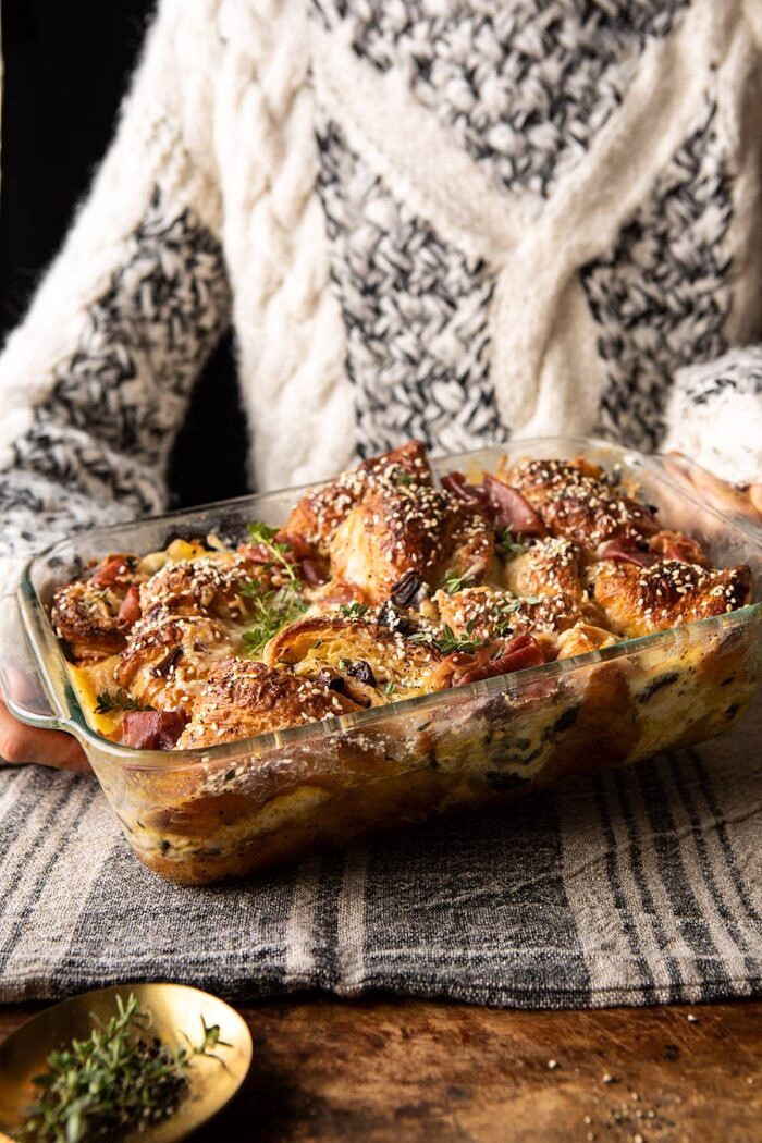 Ham and Cheese Croissant Bake | halfbakedharvest.com #brunch #breakfast #holiday #Christmas side angled photo of Ham and Cheese Croissant Bake with someone holding the dish in the background