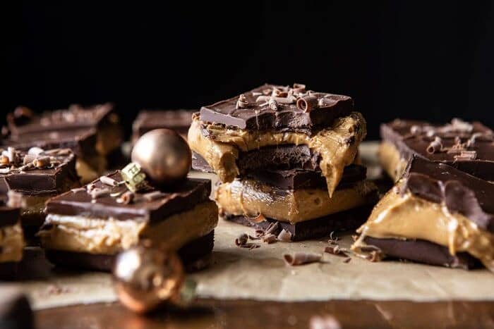 5 Ingredient Triple Decker Chocolate Peanut Butter Bars | halfbakedharvest.com #peanutbutter #chocolate horizontal photo of 5 Ingredient Triple Decker Chocolate Peanut Butter Bars with large bite taken out of bar