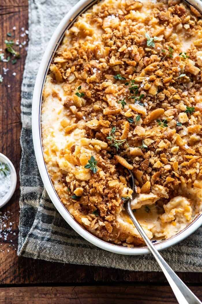 Cheesy Potato Casserole with Buttery Ritz Crackers | halfbakedharvest.com #cheesypotatoes #Christmasrecipes #potatocasserole overhead close up photo of Cheesy Potato Casserole with Buttery Ritz Crackers and spoon in casserole dish