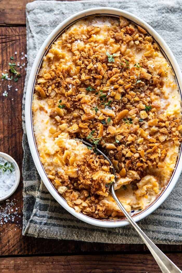 Cheesy Potato Casserole with Buttery Ritz Crackers | halfbakedharvest.com #cheesypotatoes #Christmasrecipes #potatocasserole overhead photo of Cheesy Potato Casserole with Buttery Ritz Crackers with spoon in baking dish