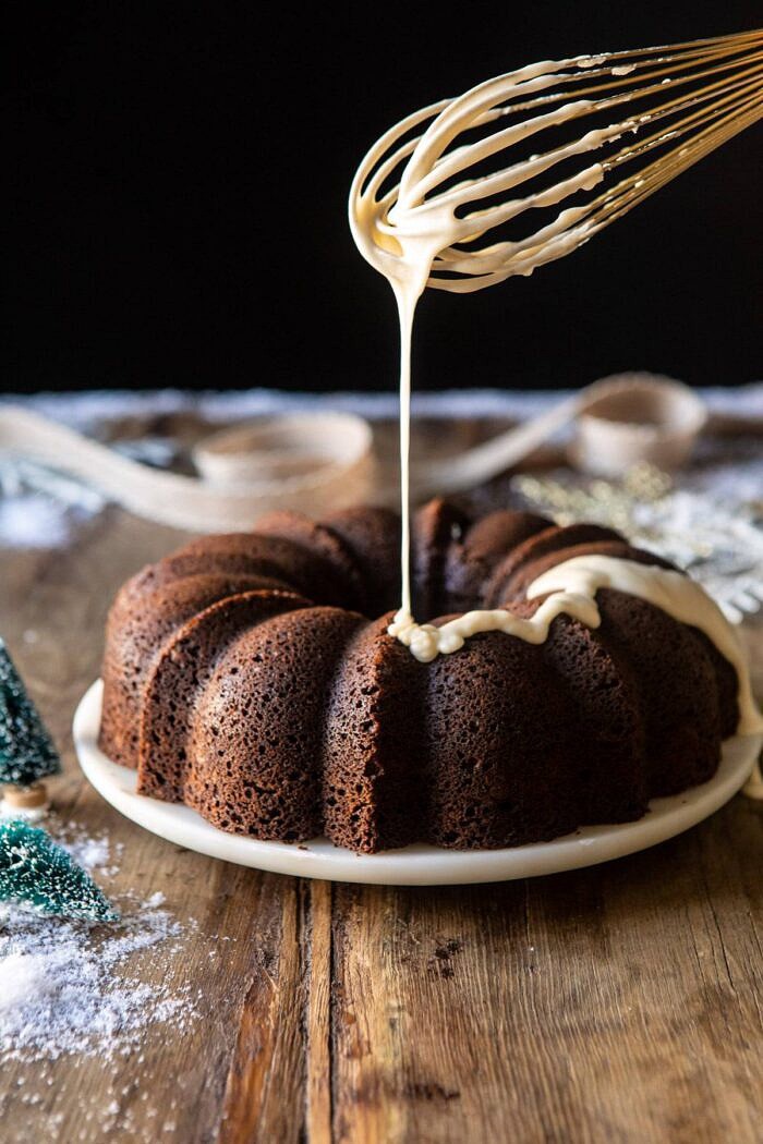 Cream Cheese Swirled Chai Gingerbread Cake | halfbakedharvest.com #gingerbread #cake #Christmas #dessert side angled photo of Cream Cheese Swirled Chai Gingerbread Cake with the glaze being drizzled over the cake