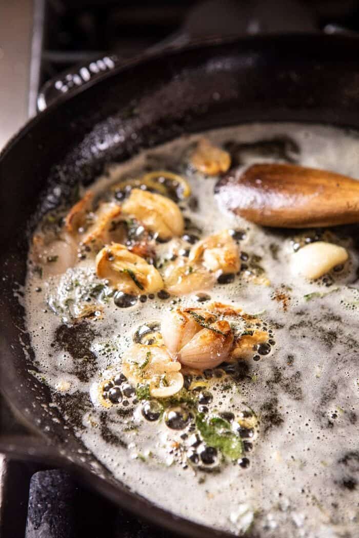 Creamy Spinach and Artichoke Salmon | halfbakedharvest.com #salmon #garlicbutter #easyrecipes side angled photo of garlic butter in skillet browning