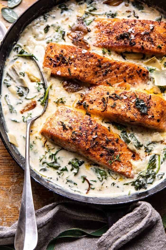 Creamy Spinach and Artichoke Salmon | halfbakedharvest.com #salmon #garlicbutter #easyrecipes overhead close up photo of Creamy Spinach and Artichoke Salmon in skillet