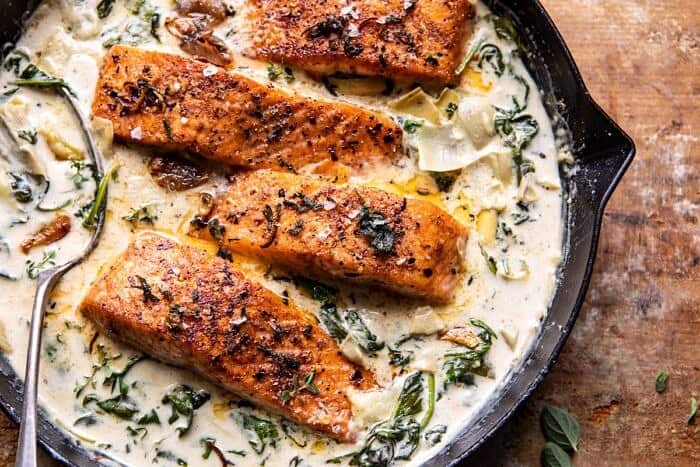 Creamy Spinach and Artichoke Salmon | halfbakedharvest.com #salmon #garlicbutter #easyrecipes overhead horizontal photo of Creamy Spinach and Artichoke Salmon in skillet